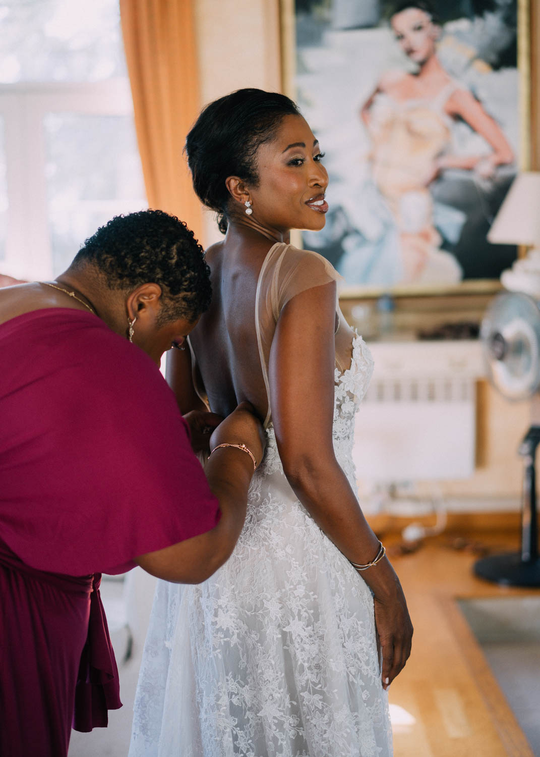 Mom in pink helps the bride into her gown before her Domaine du Mont Leuze wedding