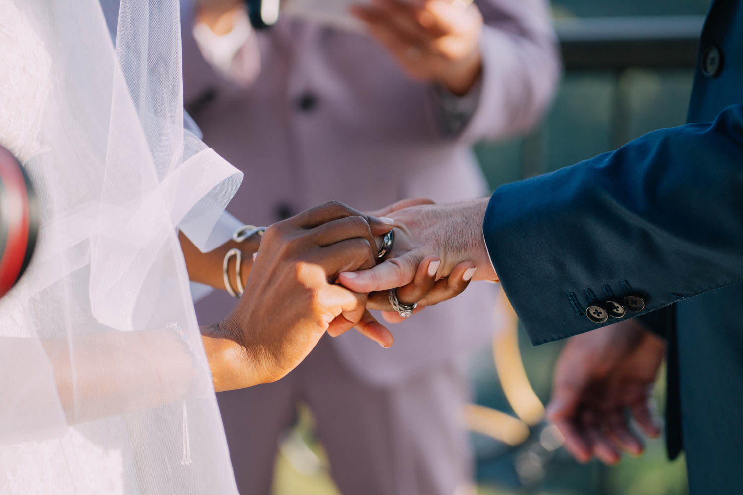 Details of a bride putting on the ring onto her groom's finger