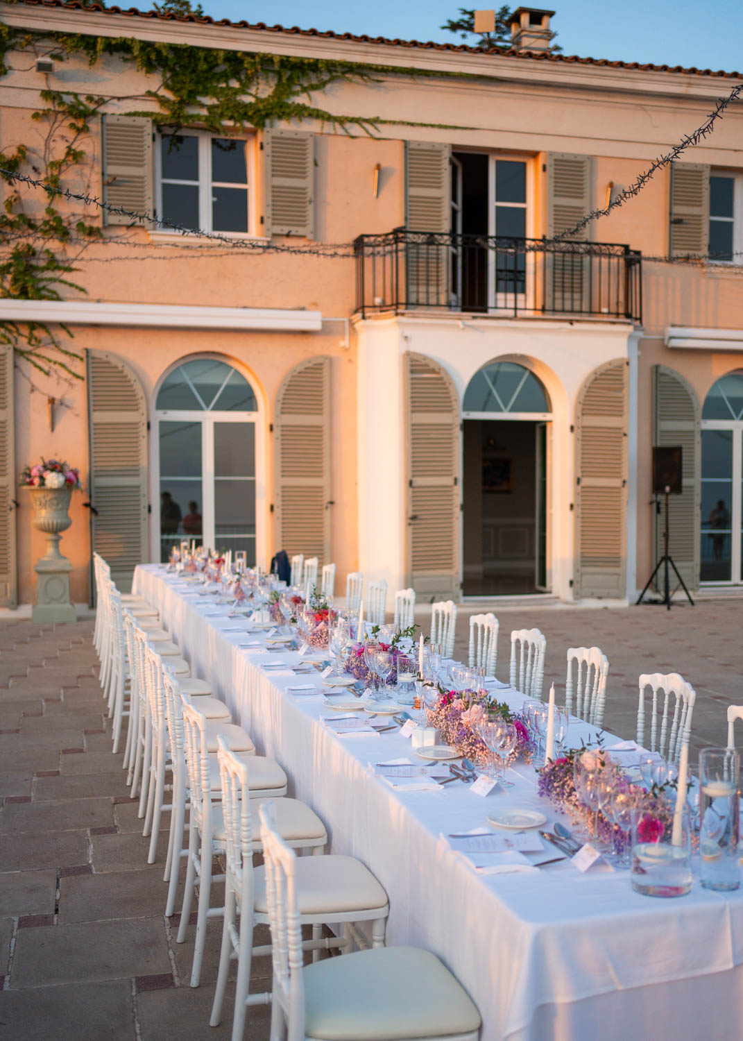 Details of a long white reception table set up with pink floral centerpieces at Domaine du Mont Leuze