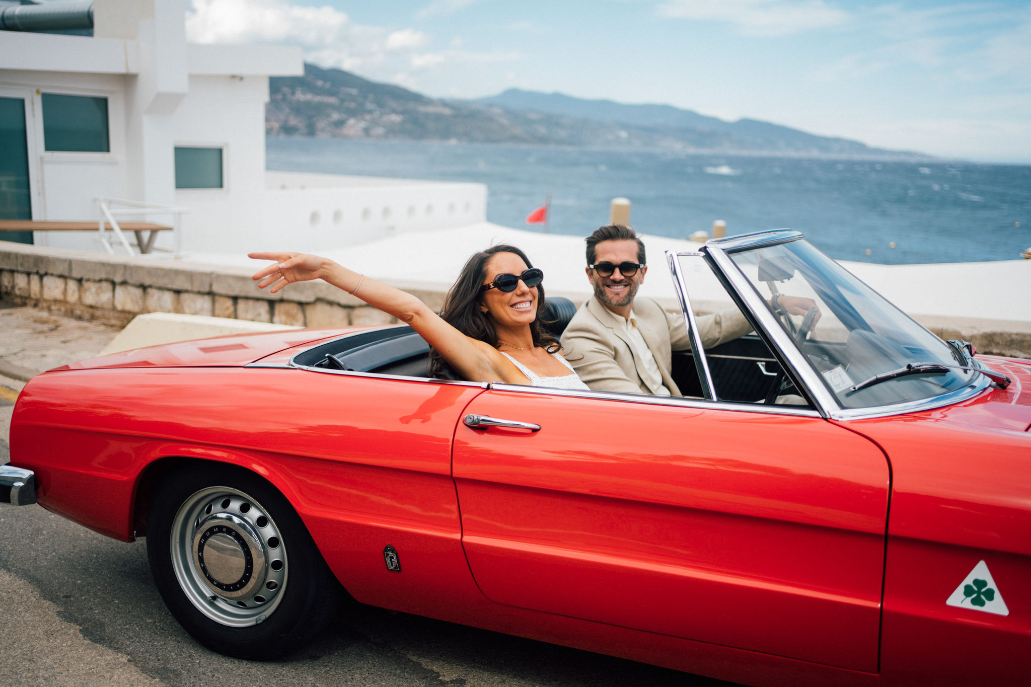 Newlyweds celebrate driving in a red convertible overlooking the water at one of the Wedding Venues In Nice France