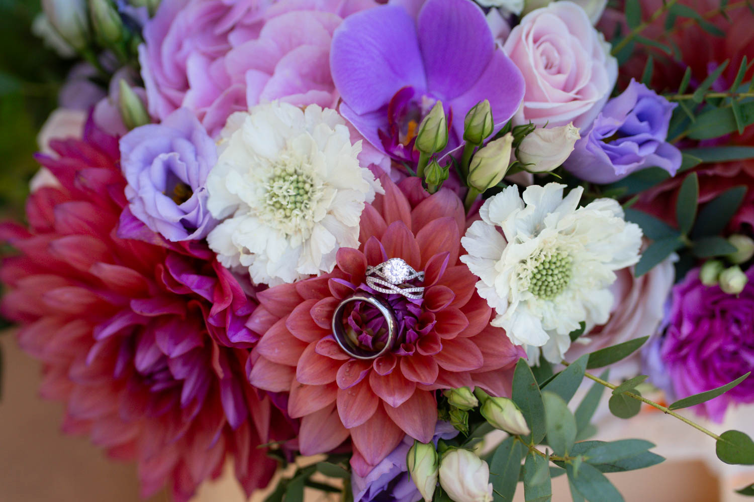 Details of wedding rings on a pink and purple bouquet