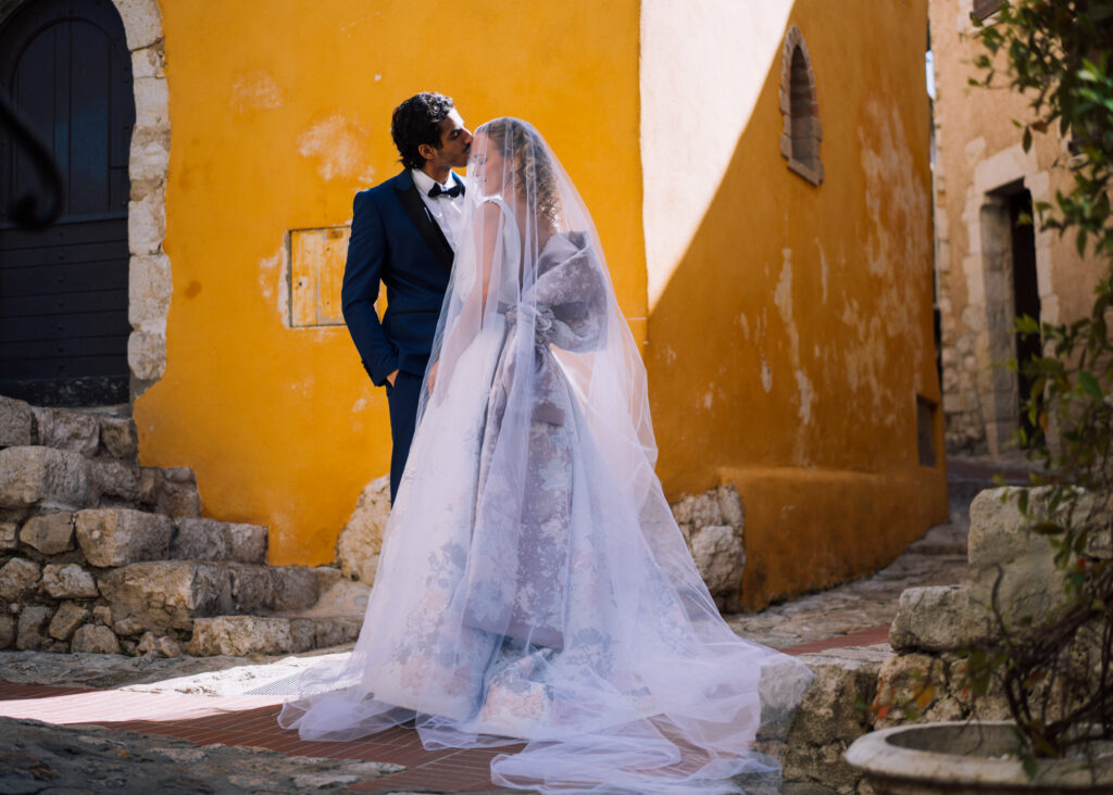 A bride is kissed while under her veil by her groom on the forehead while standing in an alley at one of the Wedding Venues Around Nice France